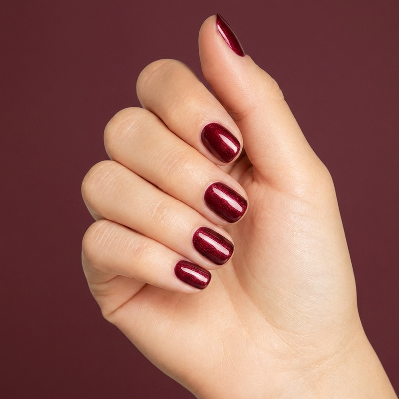 Mano con las uñas pintadas con esmalte en gel Gelish Wonder Woman, color Rojos acabado Shimmer