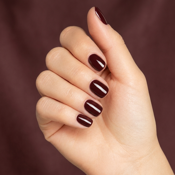 Mano con las uñas pintadas con esmalte en gel Gelish Red Alert, color Borgoñas acabado Cream