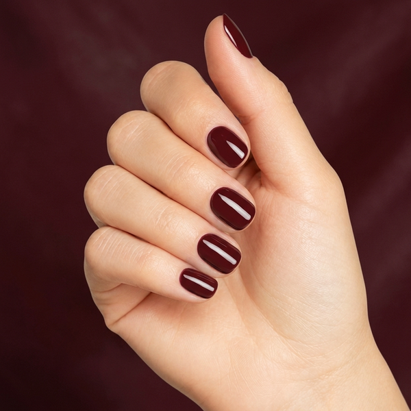 Mano con las uñas pintadas con esmalte tradicional Morgan Taylor Red Alert, color Borgoñas acabado Cream