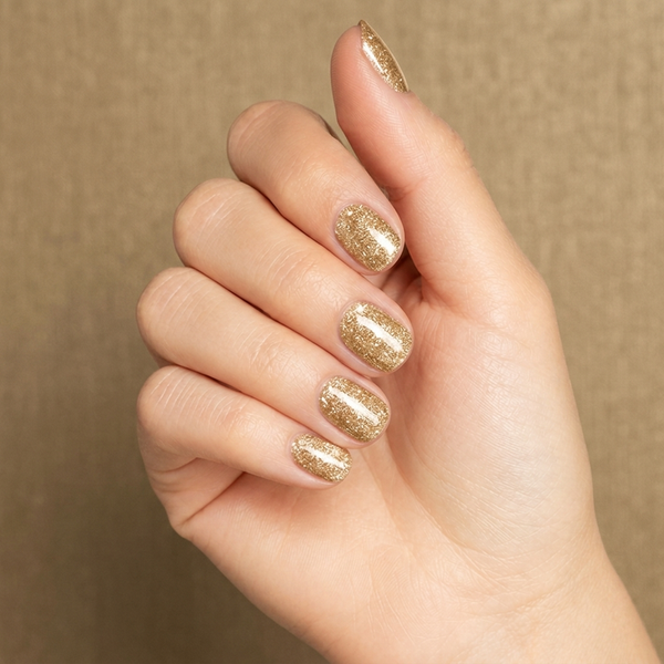 Mano con las uñas pintadas con esmalte tradicional Morgan Taylor Bronzed, color Amarillos acabado Glitter
