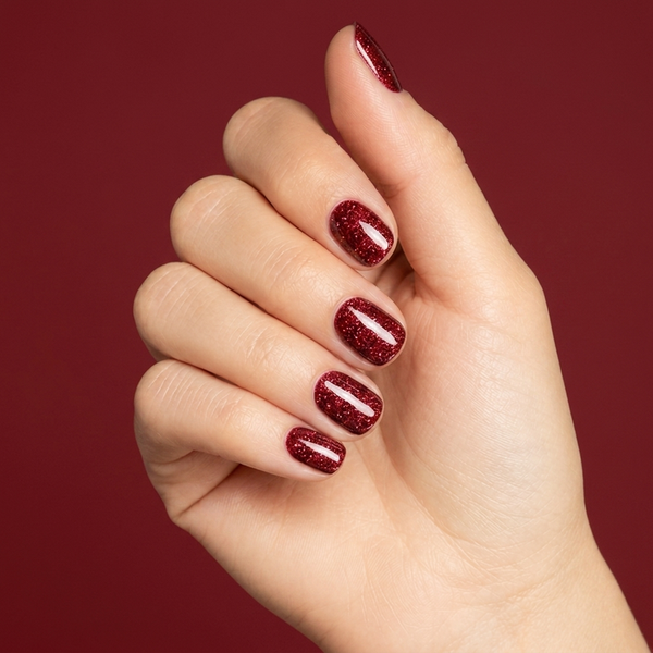 Mano con las uñas pintadas con esmalte tradicional Morgan Taylor Good Gossip, color Rojos acabado Shimmer