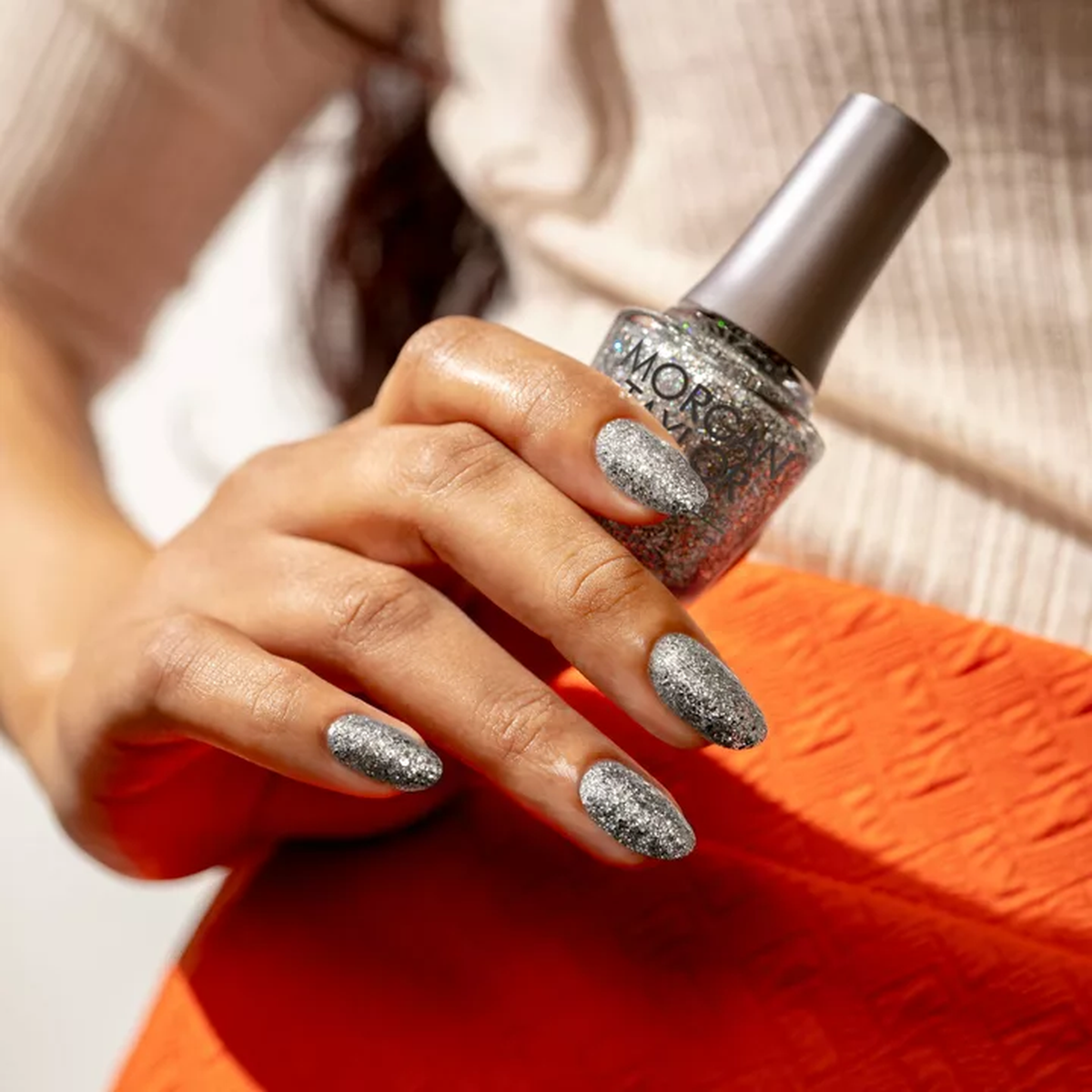 Mano con las uñas pintadas con esmalte tradicional Morgan Taylor Am I Making You Gelish?, color Blancos acabado Glitter