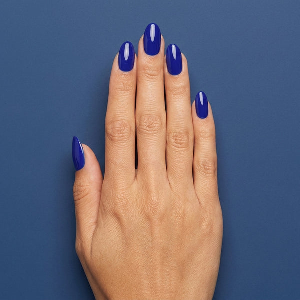 Mano con las uñas pintadas con esmalte tradicional Morgan Taylor Making Waves, color Azules acabado Cream