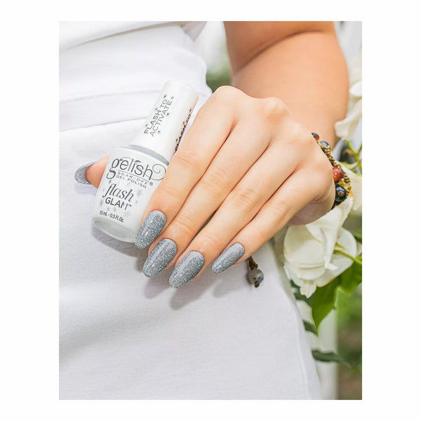 Mano con las uñas plateadas con glitter Gelish Flash Glam Dripping In Bling sosteniendo el frasco blanco con tapa FLASH TO ACTIVATE