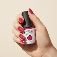 Mano sosteniendo el frasco de esmalte en gel Gelish Prettier In Pink, color Rosas acabado Cream, con las uñas pintadas del mismo tono