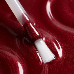 Primer plano del pincel con esmalte en gel Gelish Best Dressed, color Rojos acabado Shimmer, textura del color