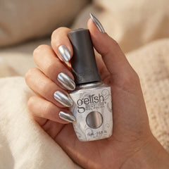 Mano sosteniendo el frasco de esmalte en gel Gelish Chain Reaction, color Blancos acabado Shimmer, con las uñas pintadas del mismo tono