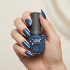 Mano sosteniendo el frasco de esmalte en gel Gelish Rhythm And Blues, color Azules acabado Glitter, con las uñas pintadas del mismo tono