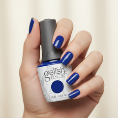 Mano sosteniendo el frasco de esmalte en gel Gelish Making Waves, color Azules acabado Cream, con las uñas pintadas del mismo tono