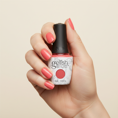 Mano sosteniendo el frasco de esmalte en gel Gelish Cancan We Dance?, color Rosas acabado Cream, con las uñas pintadas del mismo tono