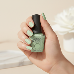 Mano sosteniendo el frasco de esmalte en gel Gelish Do You Harajuku?, color Verdes acabado Cream, con las uñas pintadas del mismo tono