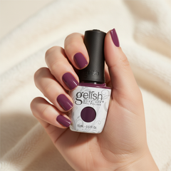 Mano sosteniendo el frasco de esmalte en gel Gelish Pop-Arazzi Pose, color Rosas acabado Cream, con las uñas pintadas del mismo tono