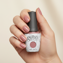 Mano sosteniendo el frasco de esmalte en gel Gelish Manga-Round With Me, color Mauves acabado Cream, con las uñas pintadas del mismo tono