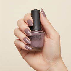 Mano sosteniendo el frasco de esmalte en gel Gelish I Or-Chid You Not, color Mauves acabado Cream, con las uñas pintadas del mismo tono