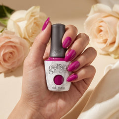Mano sosteniendo el frasco de esmalte en gel Gelish Woke Up This Way, color Rosas acabado Cream, con las uñas pintadas del mismo tono
