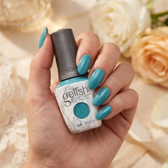 Mano sosteniendo el frasco de esmalte en gel Gelish No Filter Needed, color Azules acabado Cream, con las uñas pintadas del mismo tono