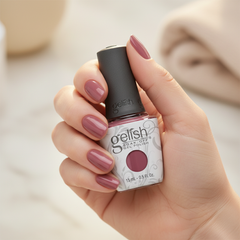Mano sosteniendo el frasco de esmalte en gel Gelish One Tough Princess, color Mauves acabado Cream, con las uñas pintadas del mismo tono