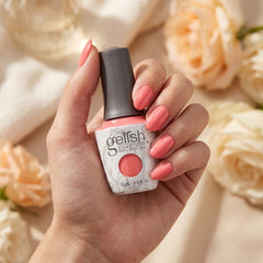 Mano sosteniendo el frasco de esmalte en gel Gelish Beauty Marks The Spot, color Rosas acabado Cream, con las uñas pintadas del mismo tono