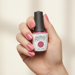 Mano sosteniendo el frasco de esmalte en gel Gelish Rose-Y Cheeks, color Rosas acabado Cream, con las uñas pintadas del mismo tono