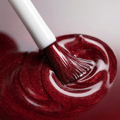 Primer plano del pincel con esmalte en gel Gelish What's Your Poinsettia?, color Rojos acabado Shimmer, textura del color