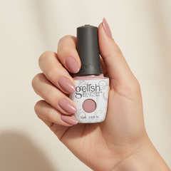Mano sosteniendo el frasco de esmalte en gel Gelish Call My Blush, color Rosas acabado Cream, con las uñas pintadas del mismo tono