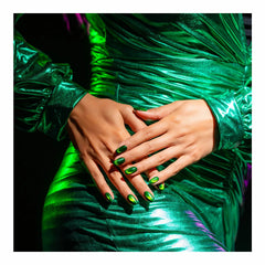 Manos con las uñas pintadas con Gelish Cat Eye Magnetic Reflections Green Lights Only sobre tela verde metálica