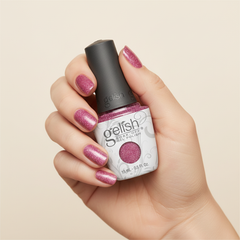 Mano sosteniendo el frasco de esmalte en gel Gelish My Best Selfie, color Rosas acabado Glitter, con las uñas pintadas del mismo tono