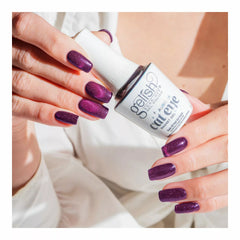 Mano con las uñas en Gelish Aurora Cat Eye Sky On Fire, ciruela oscuro con remolino rosa, sosteniendo el frasco Aurora Cat Eye Magnet Gel