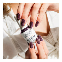 Mano con las uñas en Gelish Aurora Cat Eye Landing On Mars, borgoña casi negro con remolino naranja, sosteniendo el frasco Aurora Cat Eye Magnet Gel