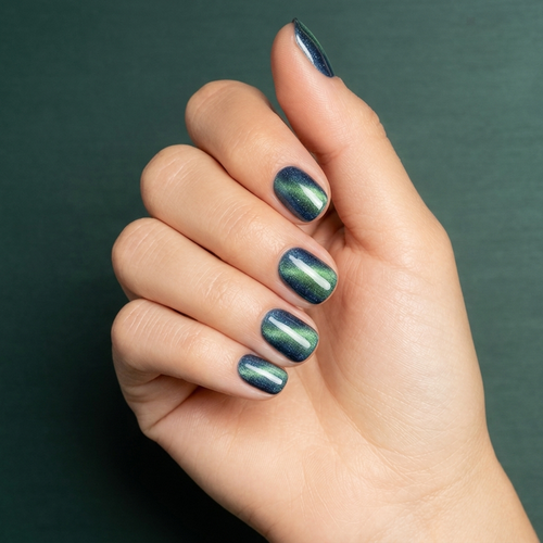 Mano con las uñas pintadas con esmalte en gel Gelish Aurora - Big Bang For Your Buck, color Verdes acabado Cat Eye