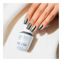 Mano con las uñas en Gelish Aurora Cat Eye Big Bang For Your Buck, verde oscuro grisáceo con remolino verde, sosteniendo el frasco Aurora Cat Eye Magnet Gel