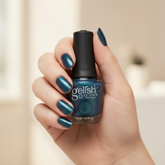 Mano sosteniendo el frasco de esmalte en gel Gelish Aurora - Come Sky With Me, color Azules acabado Cat Eye, con las uñas pintadas del mismo tono