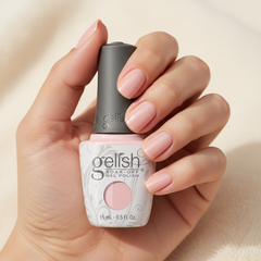 Mano sosteniendo el frasco de esmalte en gel Gelish Simple Sheer, color Nudes acabado Cream, con las uñas pintadas del mismo tono