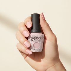Mano sosteniendo el frasco de esmalte en gel Gelish Ambience, color Rosas acabado Shimmer, con las uñas pintadas del mismo tono