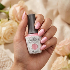 Mano sosteniendo el frasco de esmalte en gel Gelish Light Elegant, color Rosas acabado Cream, con las uñas pintadas del mismo tono