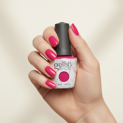 Mano sosteniendo el frasco de esmalte en gel Gelish Gossip Girl, color Rosas acabado Cream, con las uñas pintadas del mismo tono