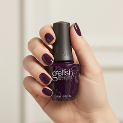 Mano sosteniendo el frasco de esmalte en gel Gelish Bella's Vampire, color Negros acabado Cream, con las uñas pintadas del mismo tono