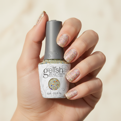 Mano sosteniendo el frasco de esmalte en gel Gelish Grand Jewels, color Blancos acabado Glitter, con las uñas pintadas del mismo tono