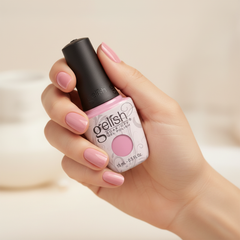 Mano sosteniendo el frasco de esmalte en gel Gelish Go Girl, color Rosas acabado Cream, con las uñas pintadas del mismo tono