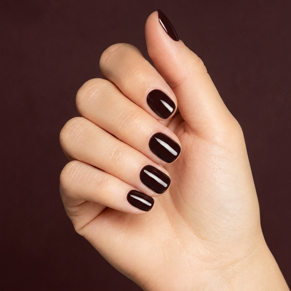 Mano con las uñas pintadas con esmalte en gel Gelish Black Cherry Berry, color Borgoñas acabado Cream