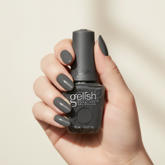 Mano sosteniendo el frasco de esmalte en gel Gelish Fashion Week Chic, color Negros acabado Cream, con las uñas pintadas del mismo tono