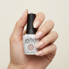 Mano sosteniendo el frasco de esmalte en gel Gelish Cashmere Kind Of Gal, color Mauves acabado Cream, con las uñas pintadas del mismo tono