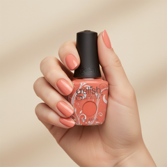 Mano sosteniendo el frasco de esmalte en gel Gelish I'm Brighter Than You, color Naranjas acabado Cream, con las uñas pintadas del mismo tono
