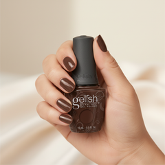 Mano sosteniendo el frasco de esmalte en gel Gelish Want To Cuddle?, color Nudes acabado Cream, con las uñas pintadas del mismo tono