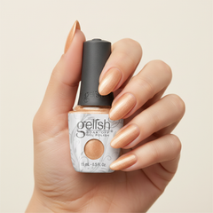 Mano sosteniendo el frasco de esmalte en gel Gelish Izzy Wizzy Let's Get Busy, color Amarillos acabado Shimmer, con las uñas pintadas del mismo tono