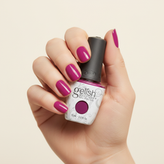 Mano sosteniendo el frasco de esmalte en gel Gelish Tahiti Hottie, color Morados acabado Cream, con las uñas pintadas del mismo tono