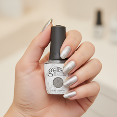 Mano sosteniendo el frasco de esmalte en gel Gelish Am I Making You Gelish?, color Blancos acabado Glitter, con las uñas pintadas del mismo tono