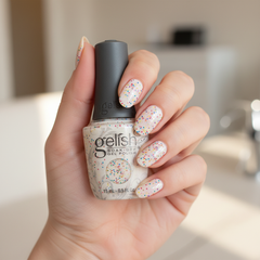 Mano sosteniendo el frasco de esmalte en gel Gelish Lots Of Dots, color Blancos acabado Glitter, con las uñas pintadas del mismo tono