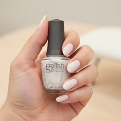 Mano sosteniendo el frasco de esmalte en gel Gelish Sheer & Silk, color Blancos acabado Cream, con las uñas pintadas del mismo tono