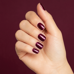 Mano con las uñas pintadas con esmalte tradicional Morgan Taylor A Tale Of Two Nails, color Borgoñas acabado Cream